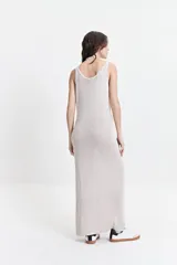 Vestido largo de punto color beige, con textura acanalada y escote redondo. De tiras finas y silueta al cuerpo, con tajo lateral.