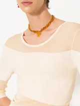 Top ajustado al cuerpo, largo hasta la primera cadera y mangas 3/4. Combina tejido liso color crema con organza transparente en diagonal.