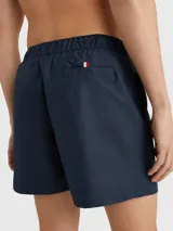 Short de baño azul marino con cintura elástica ajustable con cordón. Estampado vertical con el logo de Tommy Hilfiger en blanco y rojo en la pierna derecha.