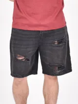 Bermuda de jean negro con roturas y corte a la rodilla.