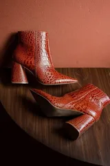 Botas cortas color marrón con estampado de cocodrilo, punta fina y taco de 8.5 cm.