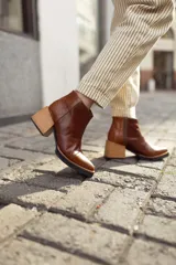Bota corta de cuero color marrón con textura reptil, caña baja, cierre lateral y taco ancho.