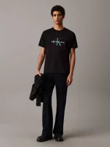 Remera negra de manga corta con cuello redondo y logo Calvin Klein Jeans estampado en el pecho con efecto brillante.