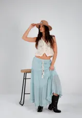 Pollera larga de color rosa pálido, con corte en capas y cintura elastizada. Incluye lazo fino del mismo material.