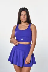 Conjunto deportivo violeta compuesto por un top corto con logo "bk." y una falda corta acampanada.