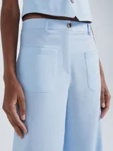 Pantalón de vestir color beige, de corte ancho y tiro alto, con bolsillos delanteros y traseros.