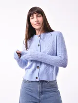 Cardigan tejido de punto color celeste con diseño de trenzas y botones marrones.