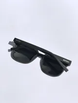 Lentes de sol negros con marco cuadrado y detalles rojos. Lentes con protección UV 400 y tecnología polarizada. Marca Osten, modelo Bali 2602.