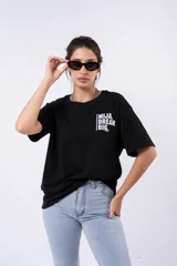 Remera negra de corte oversize con estampado frontal que dice "MIJA DREAM BIG" en tipografía blanca y rosa.