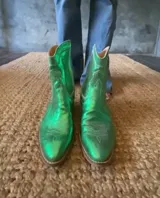 Bota corta de cuero metalizado color verde, con bordados de estilo tejano y taco de 5 cm.