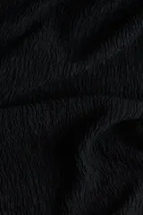 Pantalón negro de corte holgado en tejido de punto con textura. Modelo de tiro alto con cintura elástica y piernas rectas.