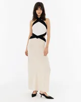 Vestido largo de lino color crudo, con escote halter cruzado en blanco y negro, y calados en los costados.