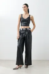Top negro de eco cuero con corte crop, breteles finos y detalle de tul en el escote.