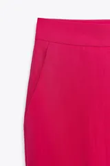 Pantalón de tiro alto color fucsia, con bolsillos delanteros y falsos bolsillos de vivo en la espalda. Tejido con efecto arrugado, pernera recta y cierre frontal con cremallera, botón interior y gancho.