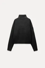 Jersey de punto color gris oscuro, de cuello alto y manga larga con terminaciones en rib.