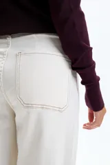 Pantalón de jean ancho color crudo con costuras a la vista en contraste.