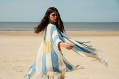 Ruana tejida en hilo de algodón con rayas horizontales en verde y blanco, y flecos en el borde inferior.
