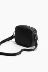 Bandolera negra con diseño trenzado, correa ajustable y cierre de cremallera.