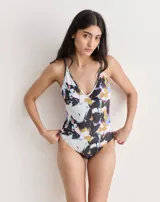 Malla entera de lycra estampada con diseño abstracto en tonos blanco, negro, amarillo y violeta. Tiene escote en V y tirantes finos.