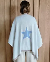 Ruana negra de tejido de punto con una estrella grande color beige en la espalda y borde inferior con franja beige.