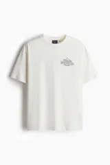 Remera color crema de corte holgado con cuello redondo y estampado de Snoopy jugando al tenis.