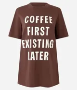Remera marrón de algodón con cuello redondo y mangas cortas. Estampa frontal con la frase "Coffee First Existin Later" en letras blancas.
