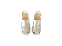 Sandalia plateada de cuero trenzado con punta cuadrada, taco ancho forrado de 4 cm, talón abierto con pulsera ajustable y hebilla metálica.