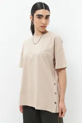 Remera oversized de algodón color beige, con manga corta, cuello a la base y botones en los laterales.