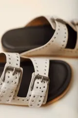 Sandalias marrones de cuero vacuno con doble tira y hebillas metálicas ajustables.