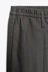 Pantalón blanco de lino, de corte ancho y tiro medio, con cintura elástica ajustable con cordones y bolsillos laterales.