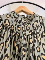 Camisa verde oliva con estampado animal print en tonos marrones y negros, cuello mao y mangas largas abullonadas.
