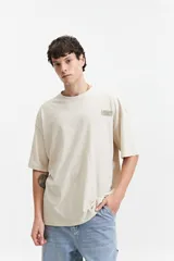 Remera gris oscuro de manga corta con corte boxy, cuello redondo y logo estampado en el pecho.