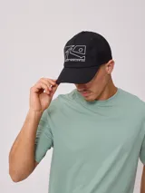 Gorra negra con visera curva y malla trasera. Presenta un estampado frontal con el logo de la marca Rusty y la leyenda "Rusty Worldwide".