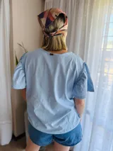 Blusa celeste de algodón con mangas cortas abullonadas.