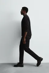 Pantalón de jean negro, corte slim fit, con tiro medio, cinco bolsillos, efecto lavado y cierre frontal con cremallera y botón.