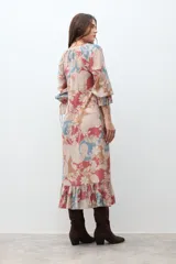 Vestido largo de manga larga, con escote en V y fruncido bajo el busto. Presenta un estampado tipo paisley en tonos rojo, azul claro y beige. El ruedo termina con un volante fruncido.