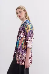 Saco de lentejuelas multicolor con forrería interna y largo a la cadera. Presenta un diseño abierto con mangas tres cuartos y una base de poliéster con forro de viscosa.