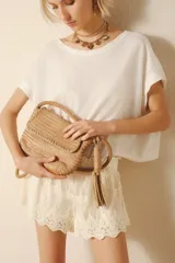 Cartera tipo tote confeccionada en cuero vacuno color beige, con diseño trenzado y cierre superior metálico. El interior está forrado y cuenta con bolsillos.
