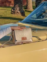 Bandolera dorada de cuero con textura tipo piel de cocodrilo, con correa larga regulable y cierre con solapa y broche imantado.