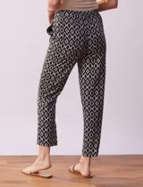 Pantalón negro con estampado geométrico blanco, de corte recto, con pretina ancha elastizada y lazo de ajuste.