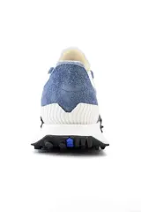 Championes urbanos New Balance de gamuza azul con detalles en gris y blanco. Presentan el logo 'N' en el lateral, cordones blancos y suela de goma negra con detalles en blanco.