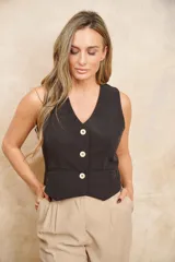 Chaleco negro con escote en V, corte sastrero y tres botones dorados. Diseño cruzado en la espalda.