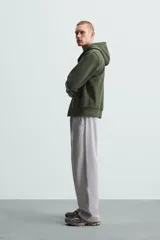 Sudadera negra con capucha ajustable, corte relaxed fit, confeccionada en tejido de algodón compacto con interior en rizo. Cuenta con manga larga, bolsillos frontales tipo canguro, acabados en rib y cierre frontal con cremallera.