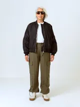 Campera bomber negra de nylon levemente acolchada con hombros caídos y corte holgado.