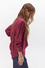 Camisa negra de manga larga con cuello clásico y cierre frontal con botones. Presenta costuras decorativas en color blanco.