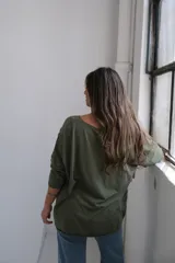 Remera verde militar con cuello en V y mangas 3/4. Presenta apliques circulares con textura en el frente y los hombros.