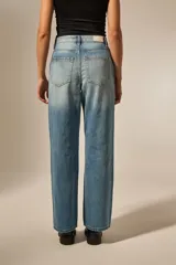 Pantalón jean negro con roturas en las rodillas, diseño de estrellas metálicas a lo largo de las costuras laterales y en los bolsillos delanteros.