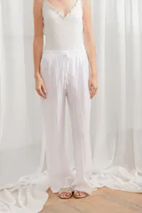Pantalón de lino blanco, de corte ancho y tiro alto, con cintura elastizada y cordón ajustable.