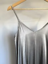 Vestido italiano amplio con escote en V, confeccionado en tela nacarada con cuerpo que aporta estructura y movimiento.