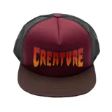 Gorro trucker con frente bordó, visera marrón y laterales de rejilla negra. Estampado frontal con el logo de Creature en degradé naranja y amarillo.